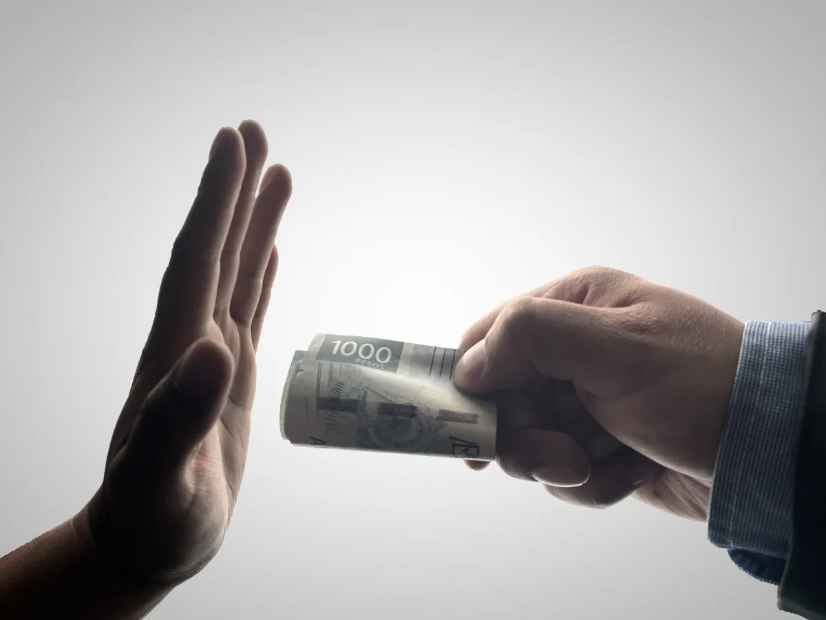 A hand refusing a bribe of cash, representing anti-bribery and corruption compliance