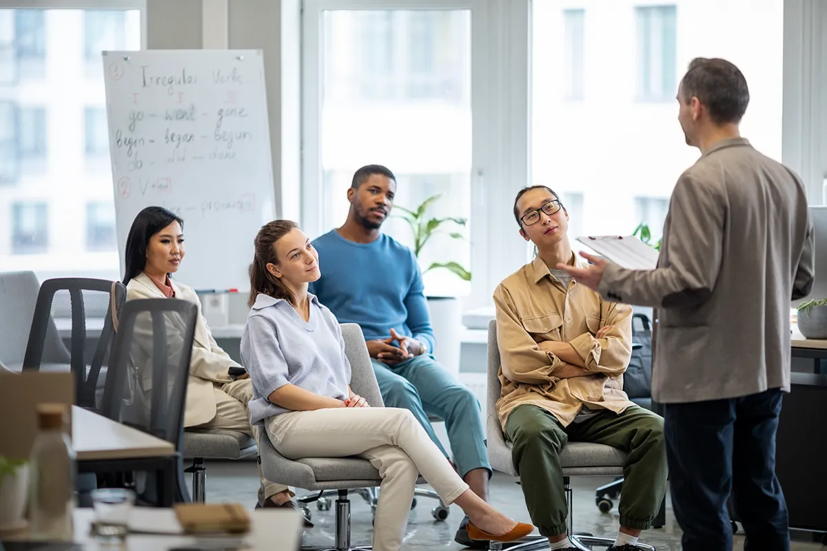 A manager coaching a small team during an office discussion