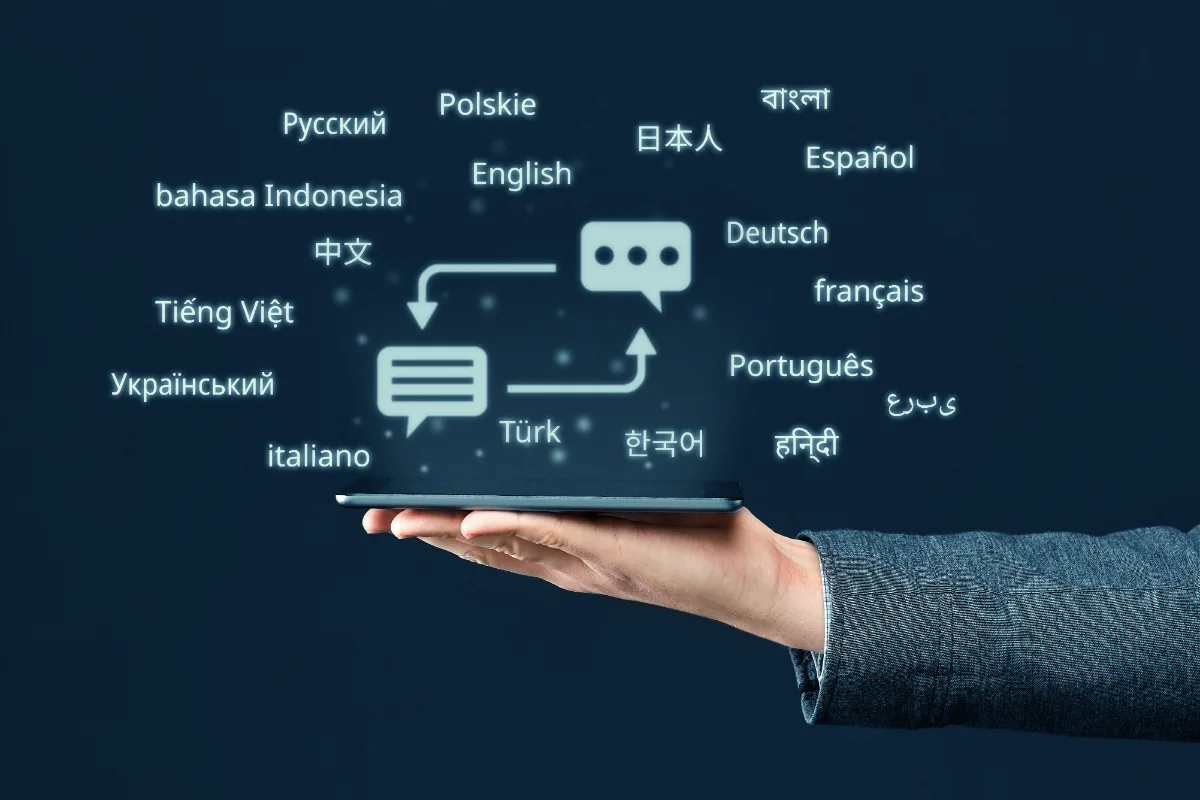 Hand holding a tablet with speech-bubble icons and language names for translation and localization